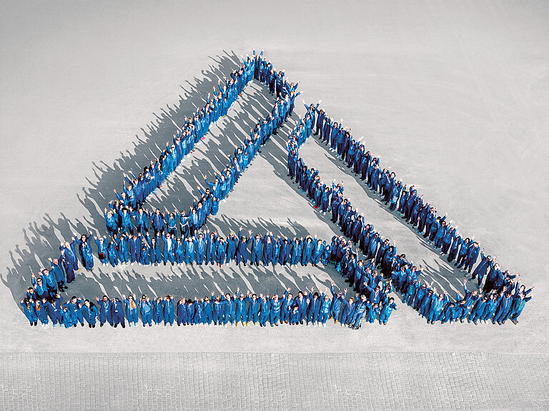Photo: Aurubis: Employees stand in the shape of the Aurubis logo.